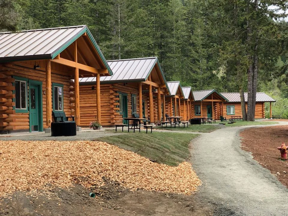 JNL job photo of log cabins with green trim in a wooded setting